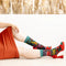 A pair of green socks with a crab-themed design. The socks feature a cute crab, a grumpy crab, and seaweed. The text 