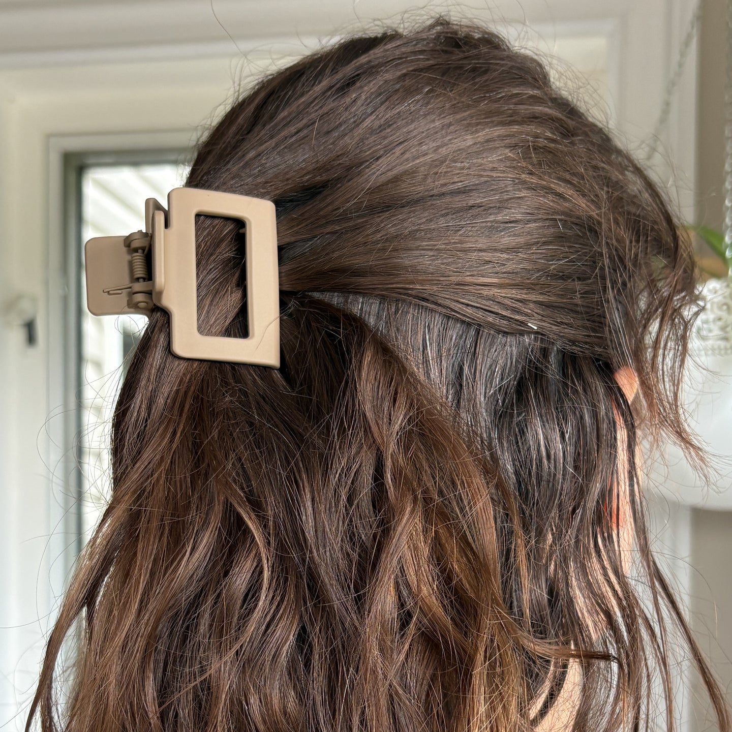 Brown hair with a gold hair clip against a neutral background