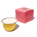 A gold metal candle tin with white wax sits in front of a pink product box labeled 'GRAPEFRUIT CARDAMOM' on a clean white background.