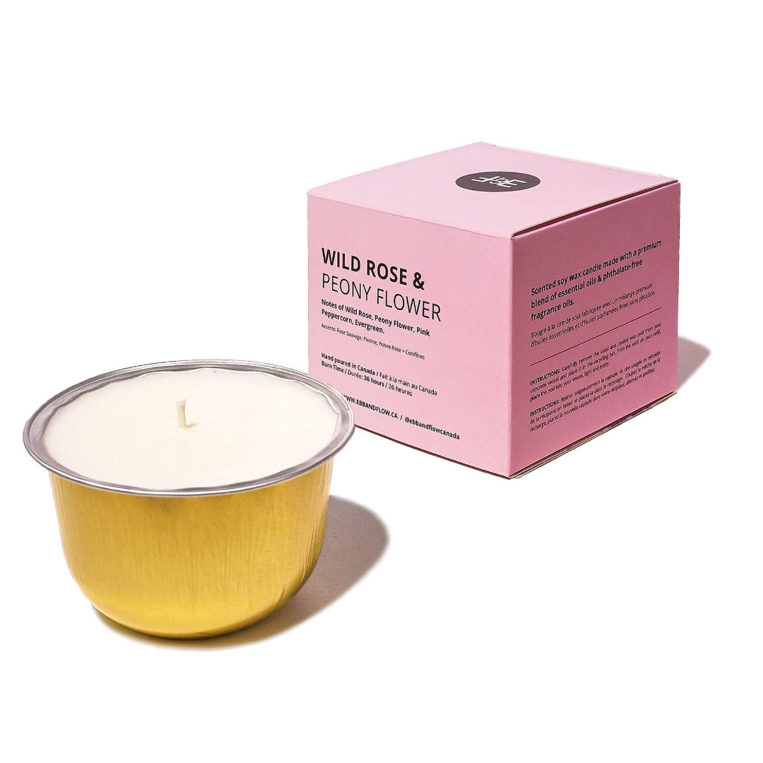 A gold metal candle tin with white wax sits in front of a pink product box labeled 'WILD ROSE & PEONY FLOWER' on a clean white background.