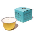 A gold metal candle bowl filled with white wax sits in front of a turquoise product box labeled 'SEA SALT & NEROLI BLOSSOM' on a clean white background.