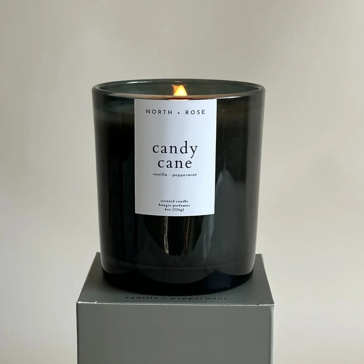 A black glass jar candle with a white label. The label reads 