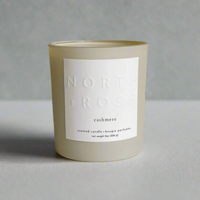 A beige glass jar candle with a white label. The label reads 