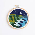 Embroidery hoop with a night scene of mountains and a river.
