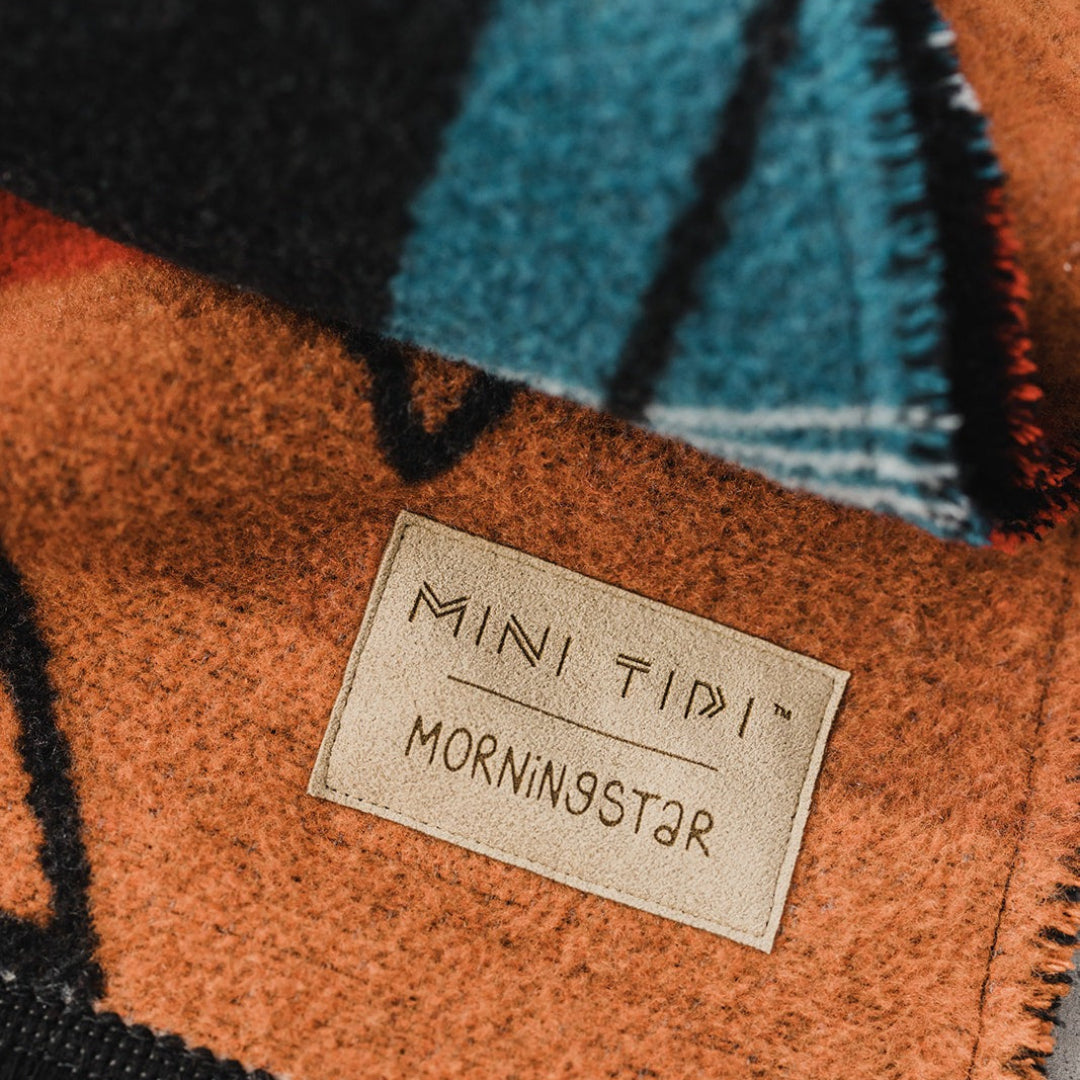 Close-up of a woven fabric with a label reading 'MINI TIPI MORNINGSTAR' on a textured background.