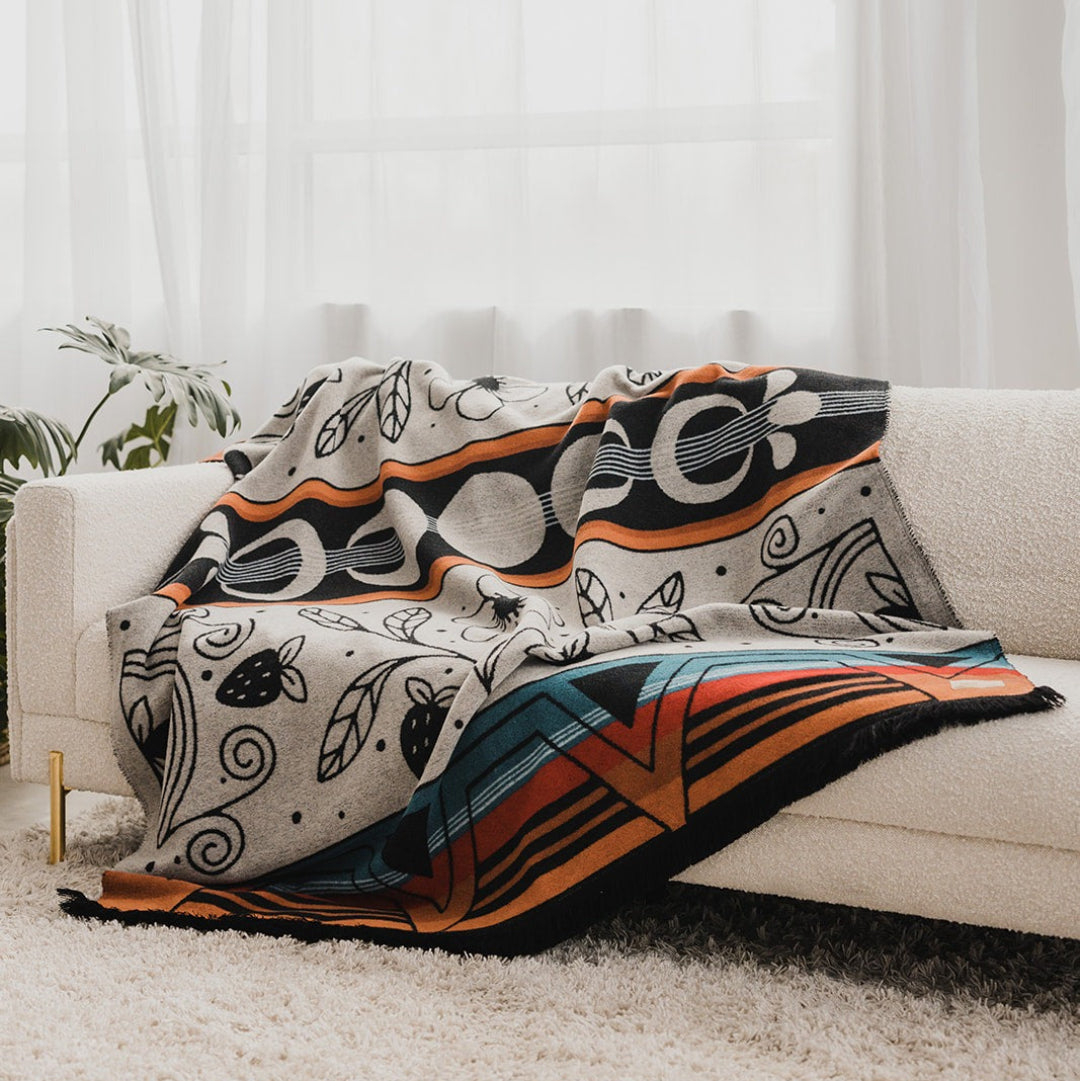 Colorful patterned blanket draped over a white sofa with a light background