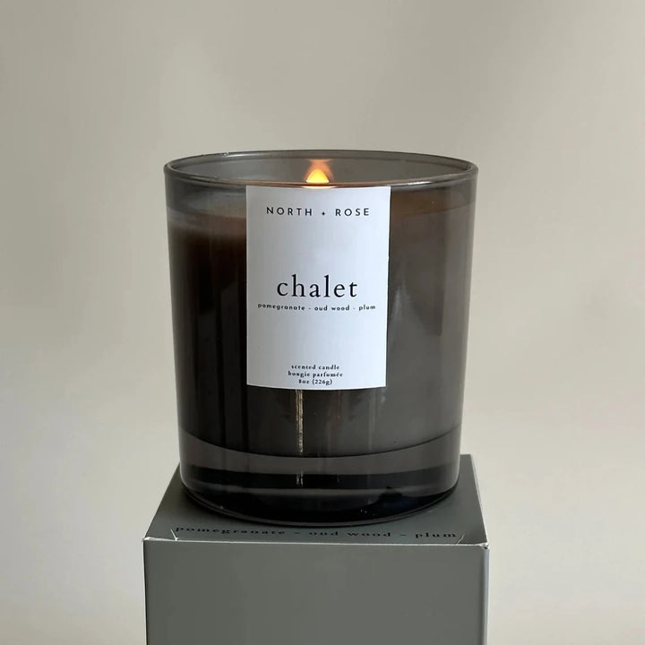 A black glass jar candle with a white label. The label reads 