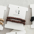 Brown hair tie on a Barbays branded card with gold and black hair ties on the side.