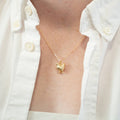 Gold necklace with a heart pendant worn by a person in a white shirt.