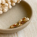 Gold bracelet on a beige ceramic dish with dried flowers