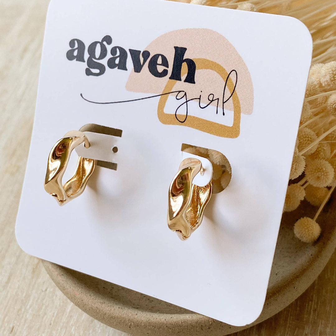 Gold hoop earrings on a 'agaveh girl' branded card with dried flowers in the background.
