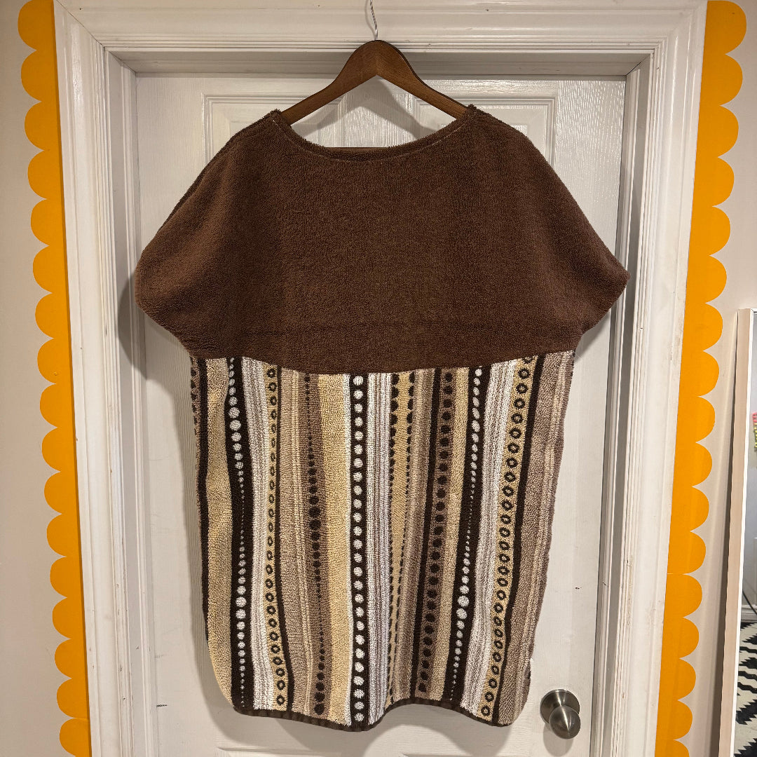 Brown and patterned dress on a hanger against a white door with decorative orange border.