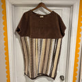 Brown and patterned dress on a hanger against a white door with decorative orange border.