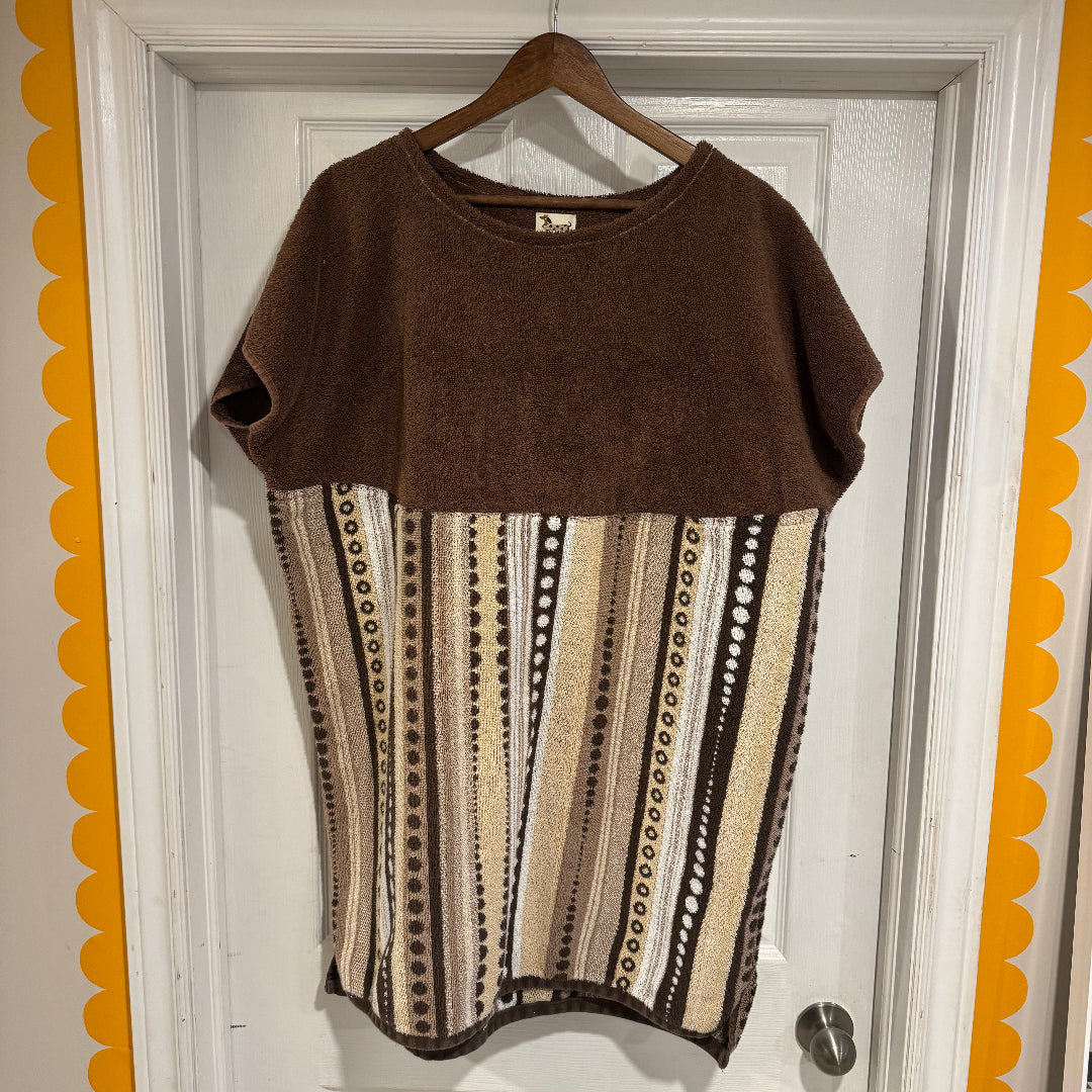 Brown and patterned dress on a hanger against a white door with decorative orange border.