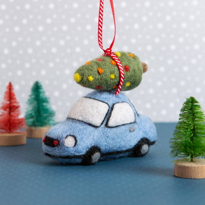 Felt blue car ornament with a Christmas tree on top, hanging against a polka dot background.