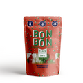 A red, resealable pouch filled with Christmas-themed gummies. The pouch has a transparent window that shows the gummies inside. The label on the pouch is in French and English and reads "BONBON BONBON," "FRAIS FRESH," "150 G," "MÉLANGE DE NOËL," and "CHRISTMAS MIX." There are also icons on the label indicating that the product is gluten-free, vegan, and made in Canada.