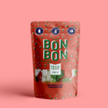 A red, resealable pouch filled with Christmas-themed gummies. The pouch has a transparent window that shows the gummies inside. The label on the pouch is in French and English and reads "BONBON BONBON," "FRAIS FRESH," "150 G," "MÉLANGE DE NOËL," and "CHRISTMAS MIX." There are also icons on the label indicating that the product is gluten-free, vegan, and made in Canada.