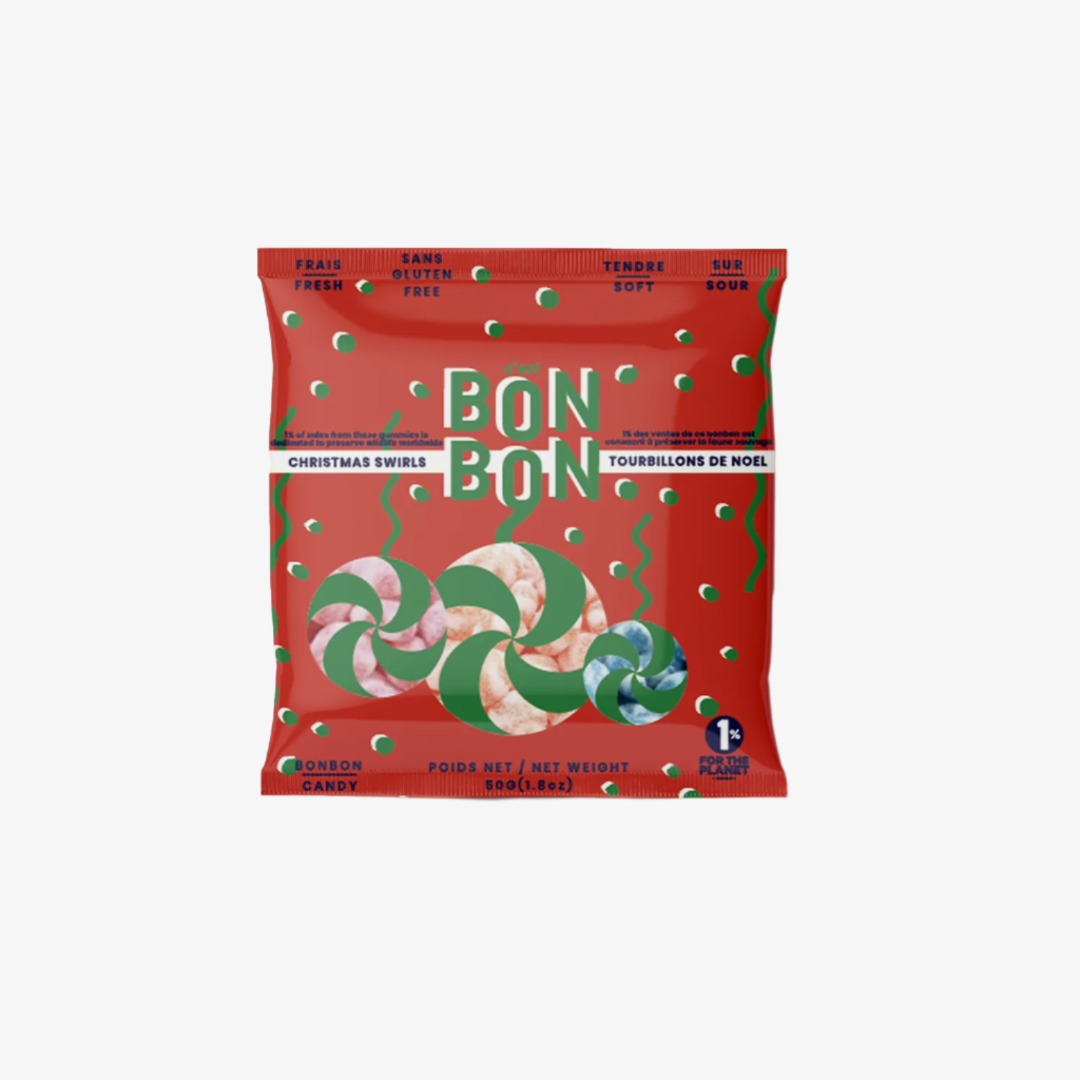  red, resealable pouch filled with Christmas-themed gummies. The pouch has a transparent window that shows the gummies inside. The label on the pouch is in French and English and reads "BONBON BONBON," "FRAIS FRESH," "TENDRE SOFT," "SANS GLUTEN GLUTEN FREE," "150 G," "MÉLANGE DE NOËL," and "CHRISTMAS SWIRLS." There are also icons on the label indicating that the product is gluten-free, vegan, and made in Canada. 