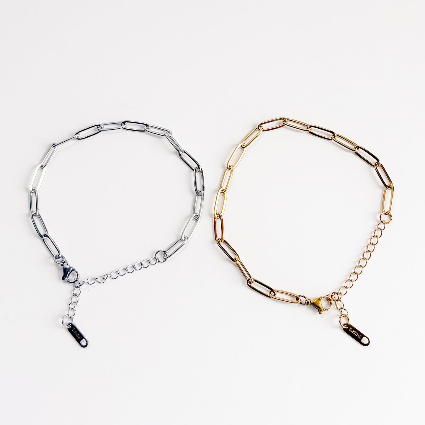 Two chain necklaces, one silver and one gold, on a white background