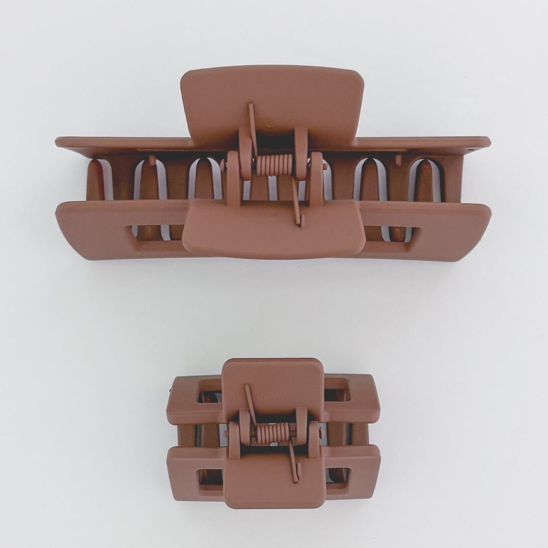 Two brown hair clamps on a white background