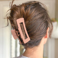 Person with a pink hair clip in their hair against a blurred background