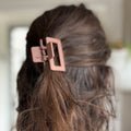 Close-up of a copper hair clip in a person's hair with a blurred background