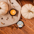 Candle with pumpkins and spices on a wooden surface