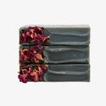 Three bars of gray soap with dried flowers on a white background