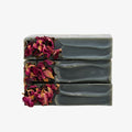 Stack of gray soap bars with dried pink and red flowers on a white background