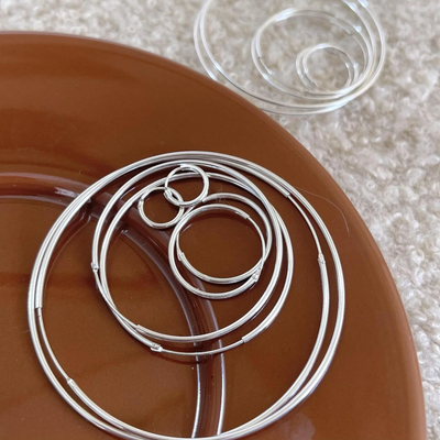 A set of classic hoop earrings made of 925 sterling silver, featuring various sizes of thin, polished silver hoops, displayed on a brown and textured surface. These simple and elegant earrings are available in Ottawa, Ontario, Canada.