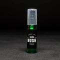 A dark green glass bottle with a black pump dispenser. The bottle is labeled "BUSH" and "CLEAN BEARD OIL." The background is black.