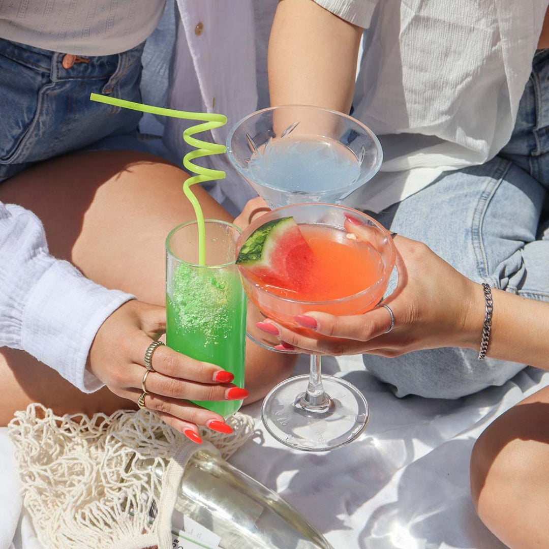 Two people holding colorful cocktails on a sunny day.