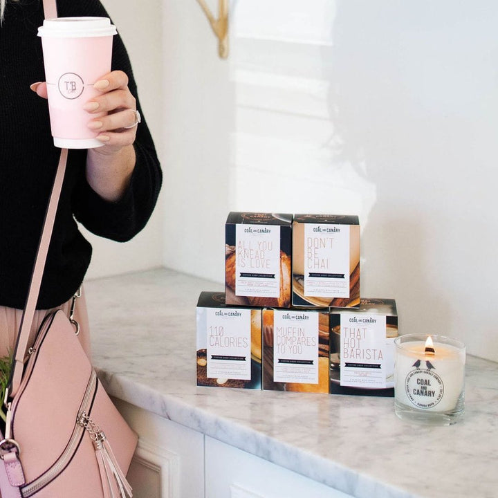 It appears to be an image of a coffee shop-themed candle and its packaging. The candle is likely scented with a coffee or bakery aroma.
