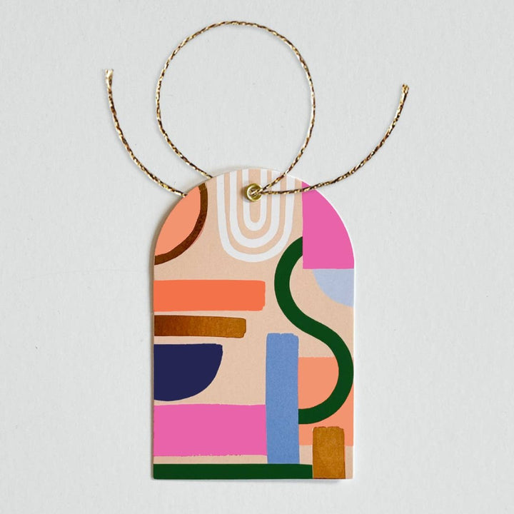 A package of 8 gift tags and twine. The tags feature a colorful abstract design with shapes and lines in various colors. The packaging is white with the Idlewild Co. logo and information about the product.