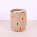 Speckled ceramic cup with colorful accents on a light background