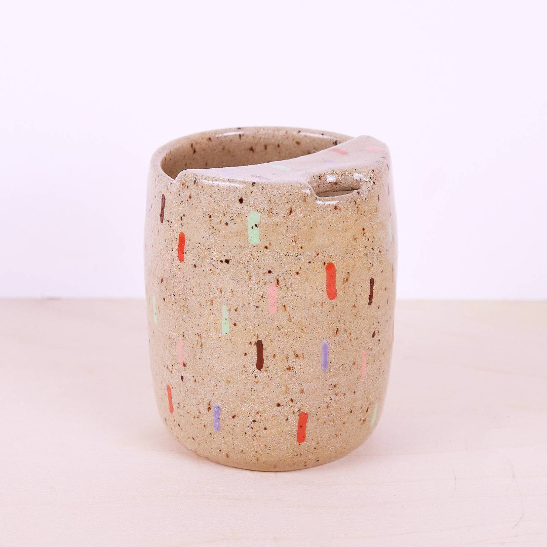 Speckled ceramic cup with colorful accents on a light background
