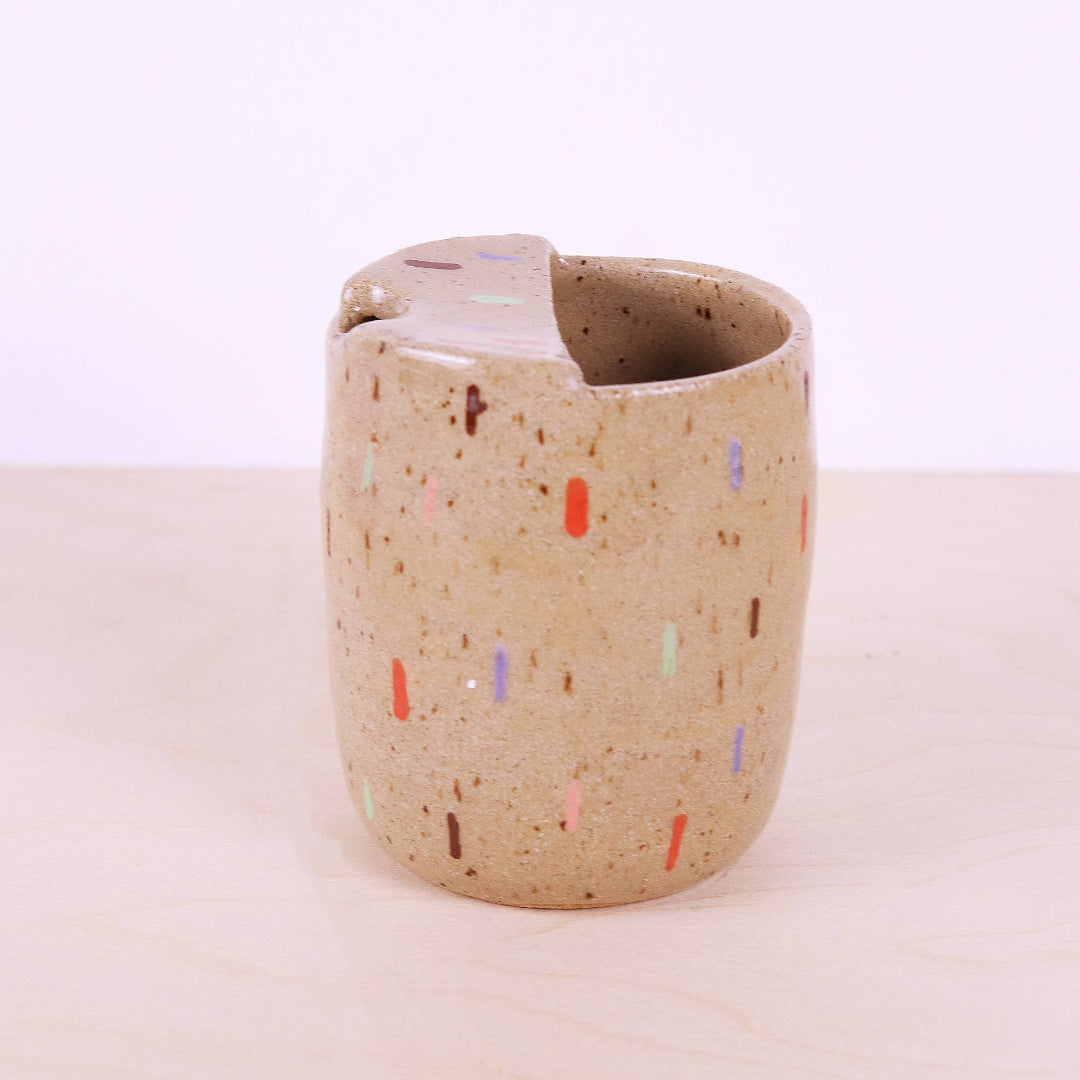 Speckled ceramic cup on a light beige background
