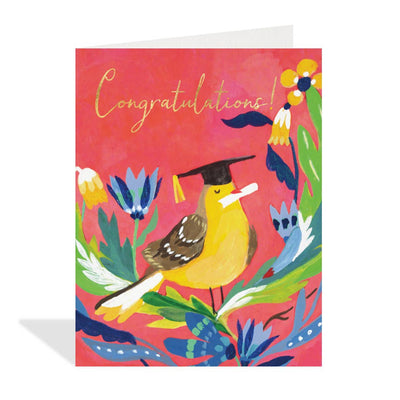 Pink greeting card featuring a colourful illustration by Canadian artist Loose Leaves of a yellow and brown bird wearing a black graduation cap with a yellow tassel and holding a rolled white diploma. The bird is surrounded by stylized blue, yellow, and white flowers and green leaves. The text 