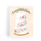 A congratulations card featuring a three-tiered wedding cake decorated with colorful flowers. The word 