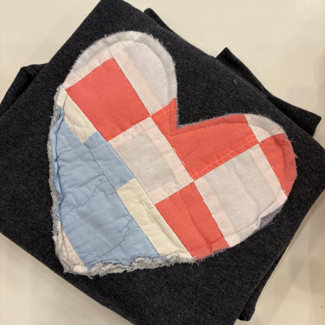 Heart-shaped quilted patchwork item on a dark fabric background