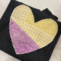 Heart-shaped patch with yellow and purple fabric on a black background
