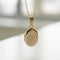 A copper oval locket necklace with an engraved evil eye design, featuring an eye with radiating lines and crescent moons, hanging from a gold chain. This is a protective and spiritual piece of jewelry, available in Ottawa, Ontario, Canada.