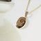 A copper oval locket necklace with an engraved design of a moon, stars, and floral elements, hanging from a gold chain. This is a celestial and elegant piece of jewelry, available in Ottawa, Ontario, Canada.