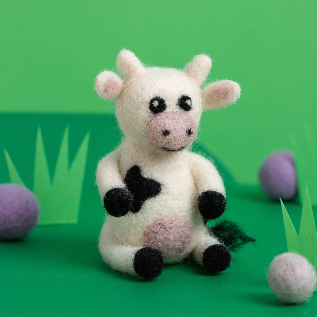 Toy cow with black spots on a green background