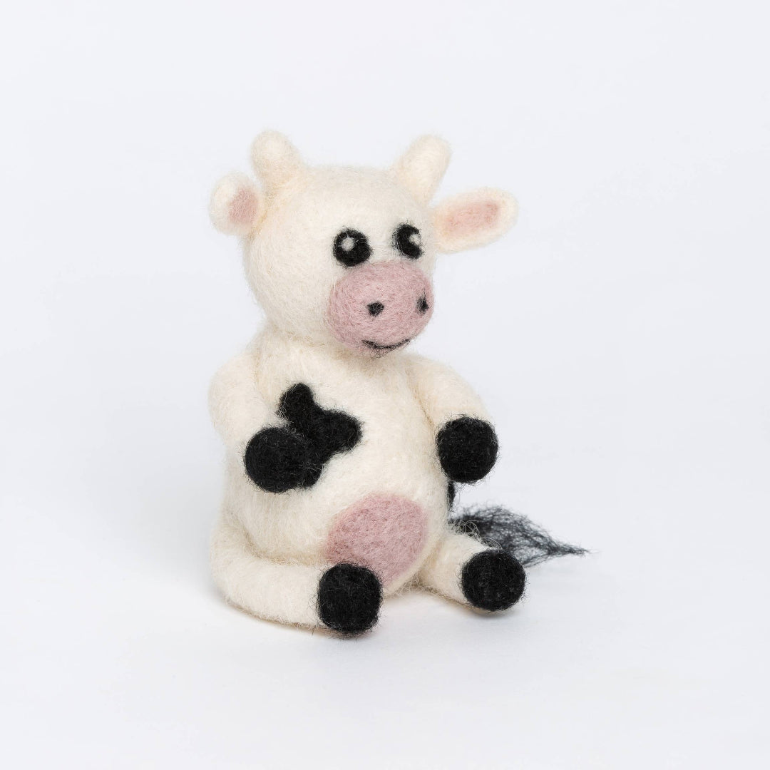 Stuffed cow toy with black spots on a white background