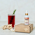 Shroom Soda bottle, glass with red liquid, and ginger root on a light background