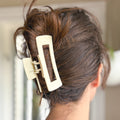 Close-up of a beige hair clip in a person's hair with a blurred background