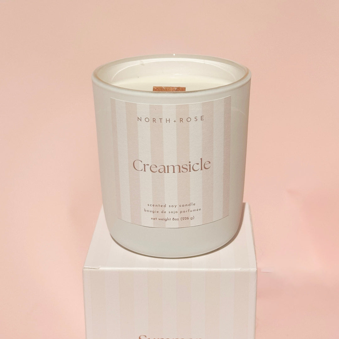 Candle labeled 'Creamsicle' by North Rose on a pink background