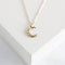 a gold-colored crescent moon pendant on a delicate gold chain.