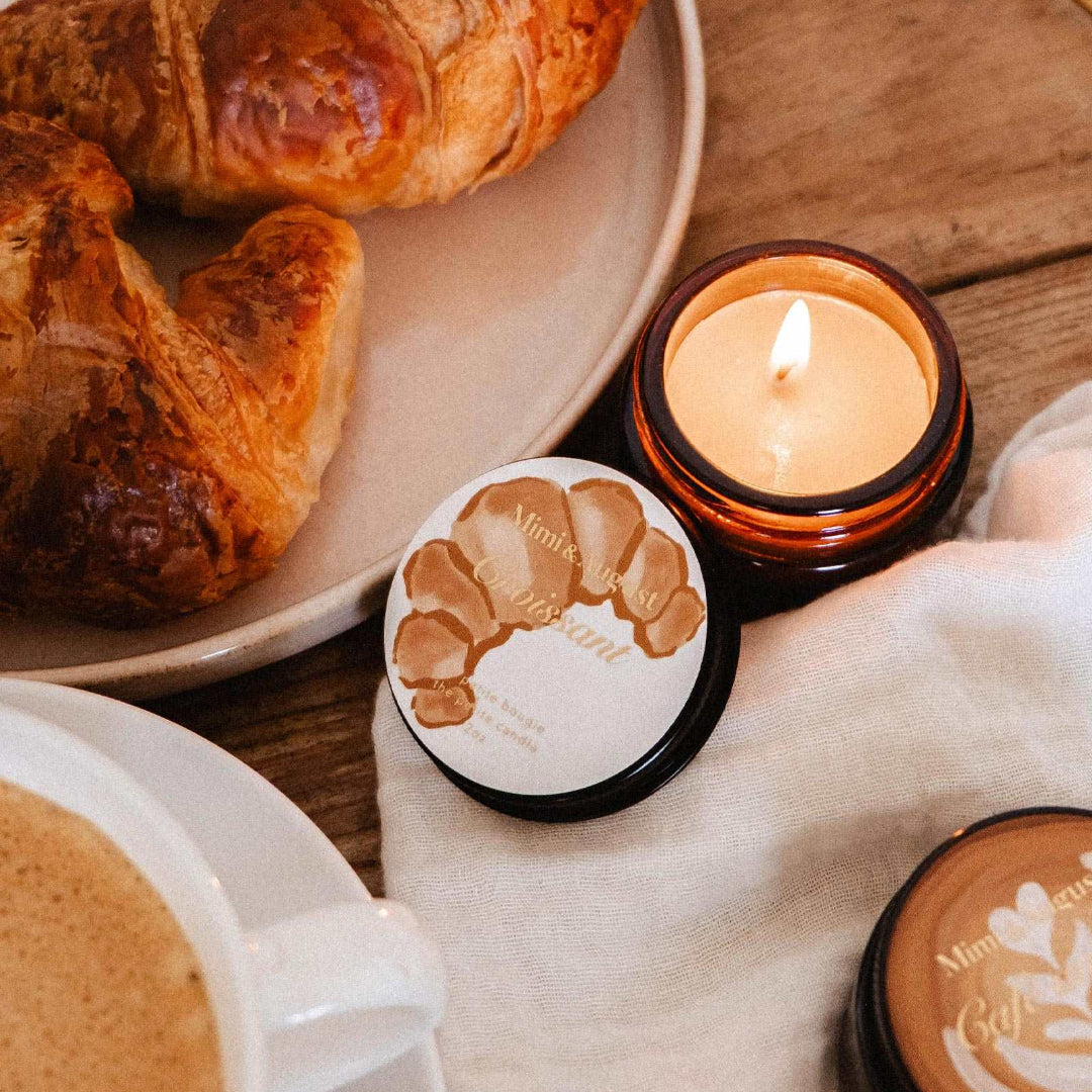 Café au lait with croissants and a lit candle on a wooden table